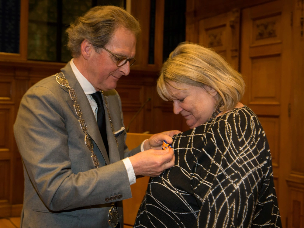 Burgemeester Rombouts spelt de versierselen op bij Annett Andriesen (foto: Marjo van de Peppel-Kool).